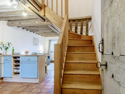 a wooden staircase in a kitchen with blue cabinets at Wheelwrights Cottage in Rumburgh