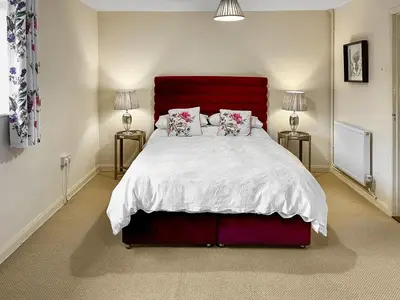a bedroom with a large bed with a red headboard at The Cottage in Fressingfield
