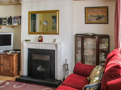 a living room with a fireplace and a red couch at Heath View Cottage in Westleton