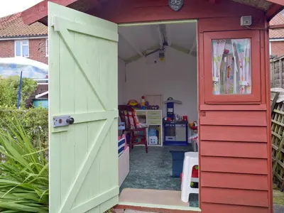 an open door into a play house with a red door at Heath View Cottage in Westleton