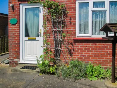 a red brick house with a white door and flowers at Heath View Cottage in Westleton