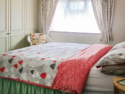 a bed with a quilt on it with a window at Heath View Cottage in Westleton