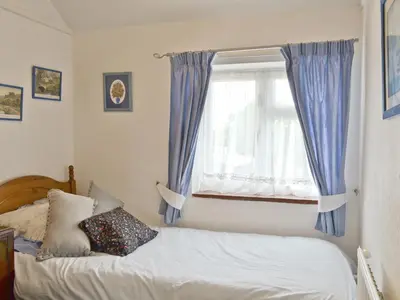 a bedroom with a bed and a window with blue curtains at Heath View Cottage in Westleton