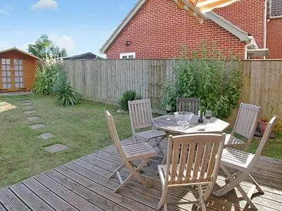 a patio with a table and chairs on a deck at Dormers in Leiston