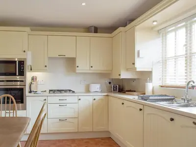 a kitchen with white cabinets and a sink at Dormers in Leiston