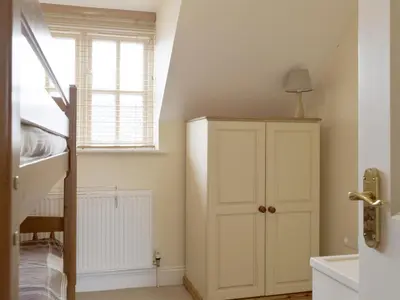 a room with a white cabinet and a staircase at Dormers in Leiston