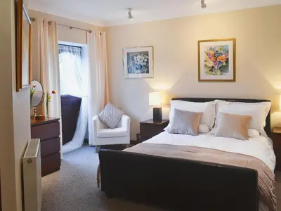 a bedroom with a bed with a chair and a window at Boundary Gallery Cottage in Framlingham