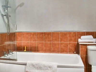 a bathroom with a bath tub and a toilet at Boundary Gallery Cottage in Framlingham