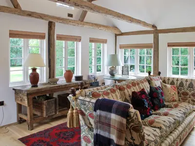 a living room with a couch and a table with windows at The Coach House in Saxmundham