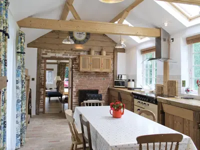 a kitchen with a table and chairs and a kitchen with a ceiling at The Coach House in Saxmundham