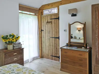 a bedroom with a mirror and a wooden dresser at The Coach House in Saxmundham