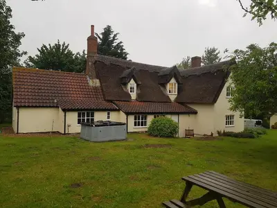 a house with a picnic table in front of it at Burnt House Cottage in Barking