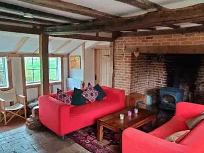 a living room with red couches and a fireplace at Burnt House Cottage in Barking