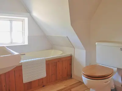 a bathroom with a toilet and a sink and a bath tub at Burnt House Cottage in Barking