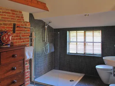 a bathroom with a shower with a toilet and a sink at Burnt House Cottage in Barking
