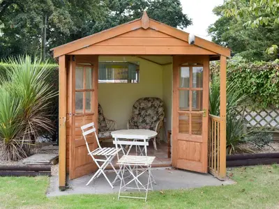 a wooden gazebo with a table and chairs in a yard at The Mount in Boxford