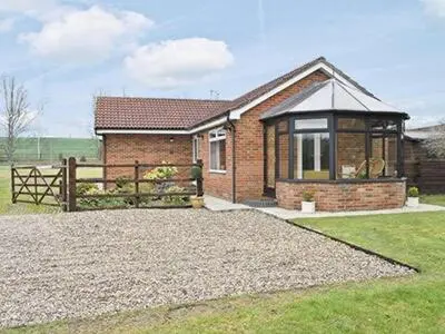 a brick house with a fence in front of it at The Lodge in Withersfield