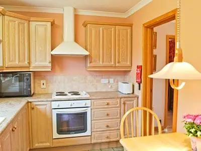 a kitchen with wooden cabinets and a stove top oven at The Lodge in Withersfield
