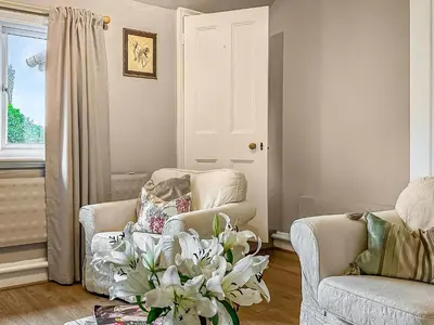 a living room with a chair and a vase of flowers at Nightingales in Hollesley