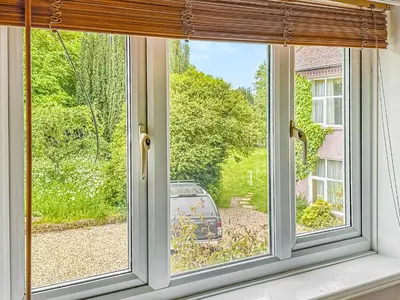 a window with a view of a car in a yard at Nightingales in Hollesley