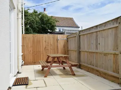 a wooden bench sitting on a patio next to a fence at Mariners Lodge in Felixstowe