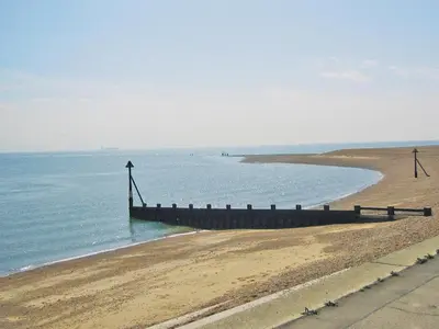 a beach with a wooden pier in the water at Mariners Lodge in Felixstowe