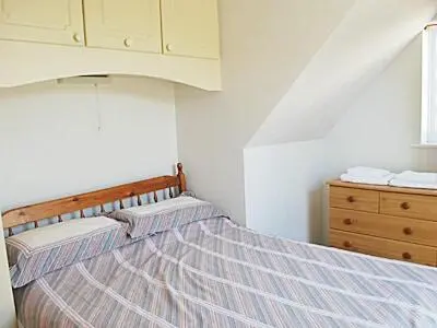 a bedroom with a bed with a wooden headboard and a dresser at Mariners Lodge in Felixstowe