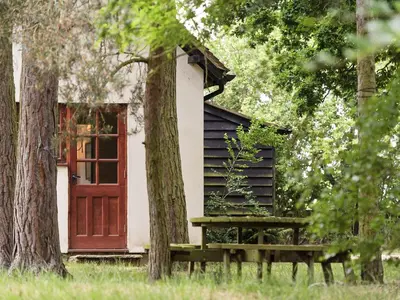 a small cabin with a red door and a bench at Coach House in Melton
