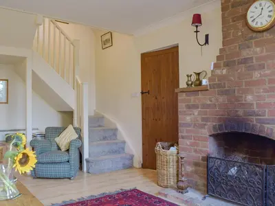 a living room with a chair and a brick fireplace at Coach House in Melton