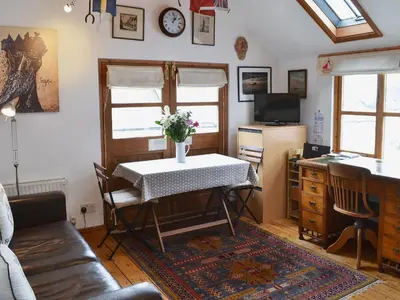 a living room with a table with flowers on it at Stoker Loft in West Mersea