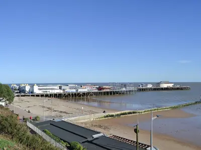 a beach with a pier in the water at Stoker Loft in West Mersea