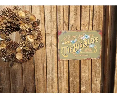 a sign on a wooden fence with wreaths on it at The Big Slepe in St Ives