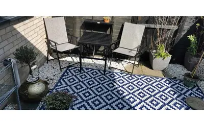 a patio with two chairs and a table on a rug at The Big Slepe in St Ives