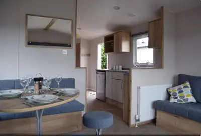 a living room with a dining table and a kitchen at Mersea Retreat in West Mersea