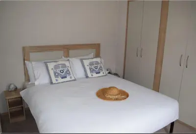 a straw hat sitting on a white bed with pillows at Mersea Retreat in West Mersea