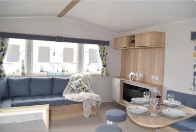 a living room with a blue couch and a table at Mersea Retreat in West Mersea