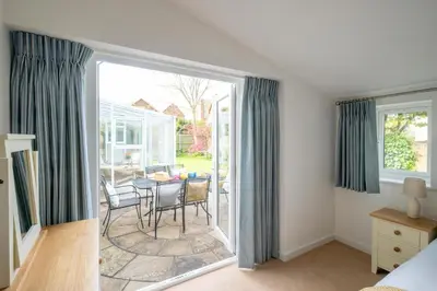 a room with a sliding glass door with a table and chairs at Annie's House in Thorpeness