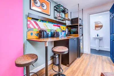 a kitchen with a bar and stools in a room at Cosy Studio flat near hospital - Pass the Keys in Westcliff On Sea