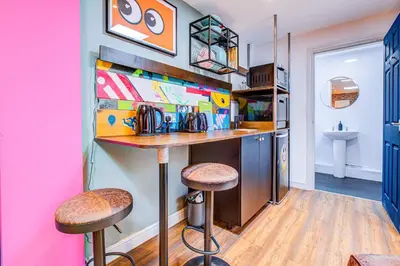 a kitchen with a bar and stools in a room at Cosy Studio flat near hospital - Pass the Keys in Westcliff On Sea