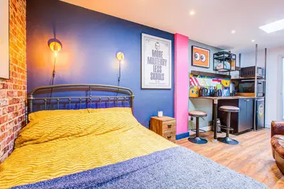 a bedroom with a yellow bed and a blue wall at Cosy Studio flat near hospital - Pass the Keys in Westcliff On Sea