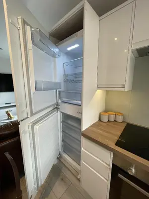 a kitchen with white cabinets and a refrigerator at Luxurious apartment just off Mill Rd, near station - walk to historic city centre in Cambridge