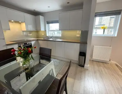 a kitchen with a glass table with a vase of flowers at Luxurious apartment just off Mill Rd, near station - walk to historic city centre in Cambridge