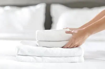 a woman is stacking towels on a bed at Luxury City CB1 Studio Just Off Mill Rd - Walk to Station and City Centre in Cambridge