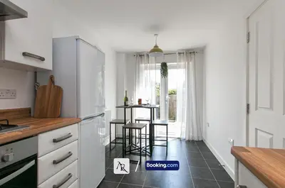 a kitchen with white cabinets and a table in the window at Stylish House By AR Properties Short Lets & Serviced Accommodation Colchester in Colchester