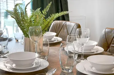 a table with glasses and plates and a plant on it at Loughton 3 Bedroom Sleeps 5 by BSE Homes in Loughton