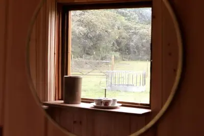 a mirror reflecting a window with a view of a field at The Falgate Shepherd's Hut in Caston