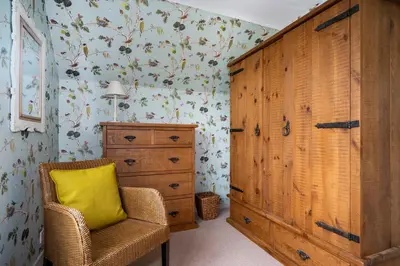a bedroom with a dresser and a yellow pillow in a chair at Pats Place in Sudbury