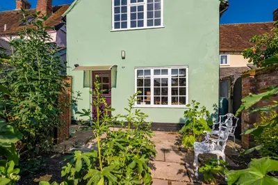 a green house with two white chairs in the garden at Pats Place in Sudbury