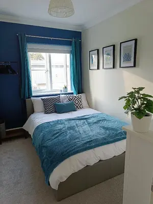 a bedroom with a bed with blue walls and a window at Modern 2-Bed Duplex - 10 Mins to City Centre in Chesterton