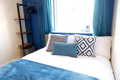 a bedroom with blue curtains and a bed with pillows at Modern 2-Bed Duplex - 10 Mins to City Centre in Chesterton